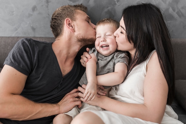 Close-up of young couple kissing their smiling son