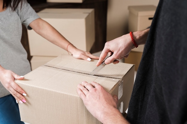 Close-up young couple preparing cardboard boxes to move