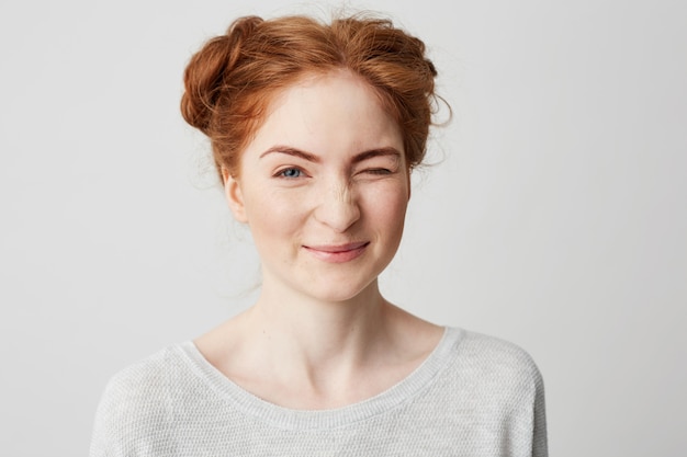 Chiuda in su di sbattere le palpebre sorridente della giovane ragazza sveglia di redhead.