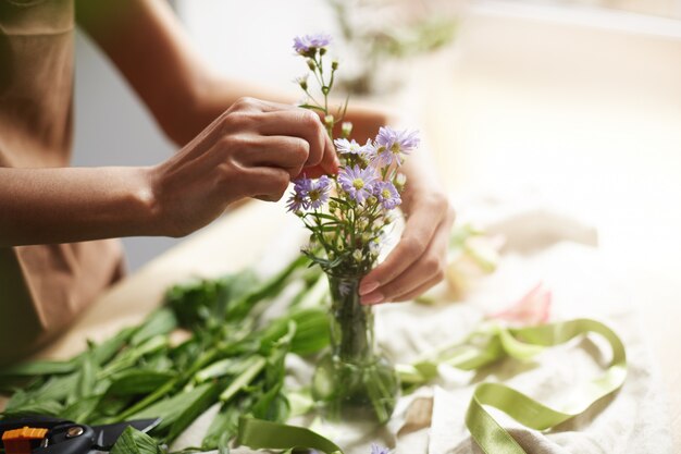 Close up of young female florist making tender bouquet at workplace. Copy space.