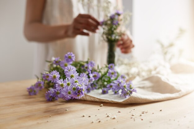 Close up of young female florist making tender bouquet at workplace. Copy space.