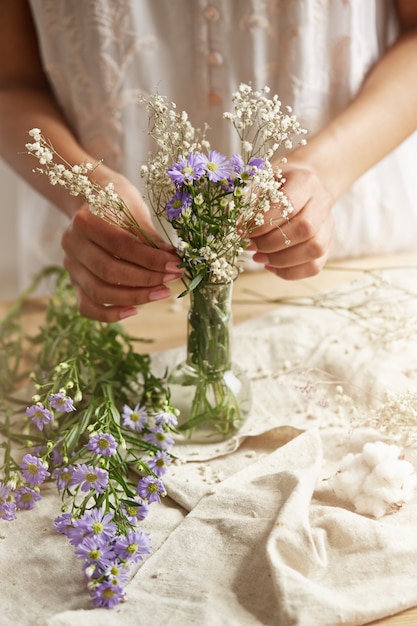 Close up of young female florist making tender bouquet at workplace. Copy space.