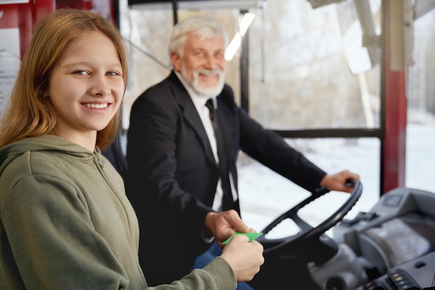 Close up of young female in olive hoodie and elderly driver together holding ticket near driver