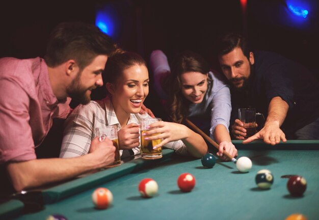 Close up on young friends having fun while playing pool game