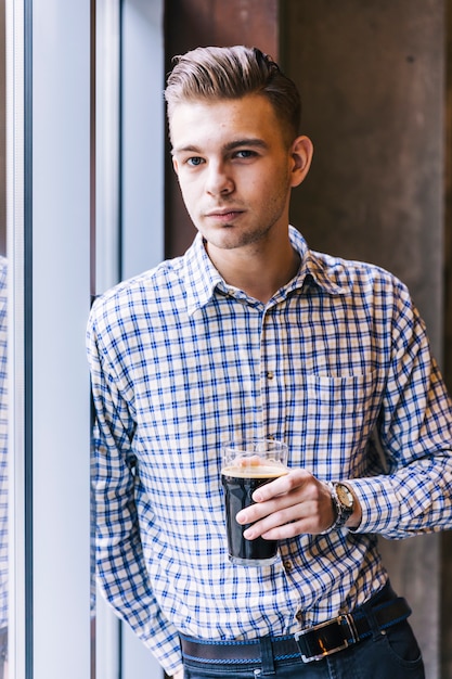 Free photo close-up of a young handsome man holding the beer glasses looking at camera