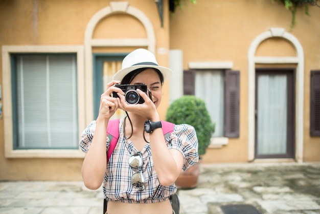 Close up of young hipster woman backpack traveling taking photo in urban.