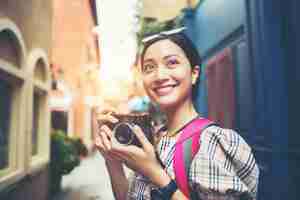 Foto gratuita chiuda su dello zaino della donna dei giovani pantaloni a vita bassa che intraprende la presa della foto con la sua macchina fotografica in urbano.