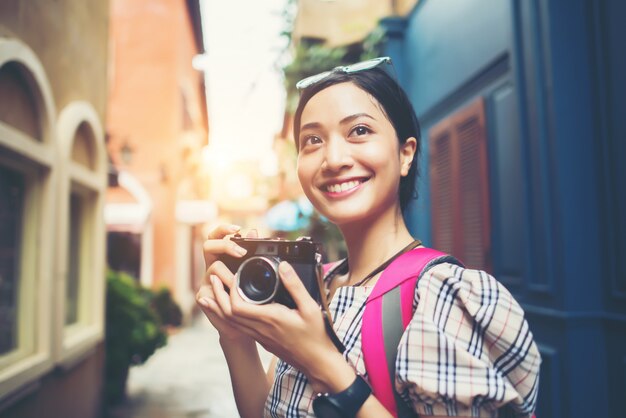 Close up of young hipster woman backpack traveling taking photo with her camera in urban.