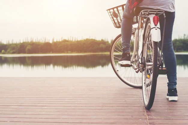 Primo piano di giovane donna pantaloni a vita bassa tenendo il piede sul peda bicicletta