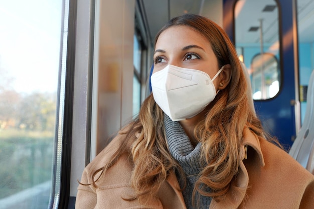 Close up of young lady wearing protective medical mask kn95 ffp2 on public transport looking through the window