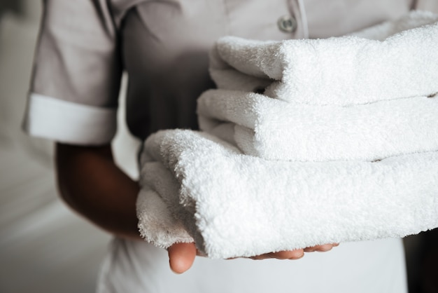 Foto gratuita primo piano di una giovane cameriera in possesso di asciugamani piegati