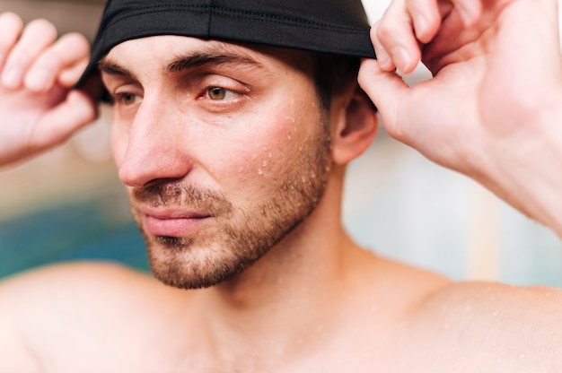 Free photo close-up young male putting on swimming cap