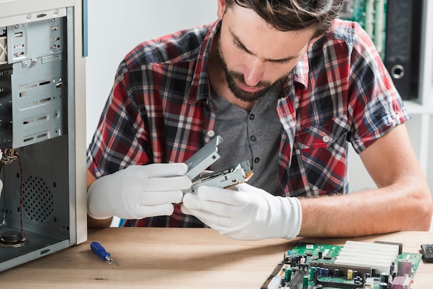 Close-up of a young male technician examining computer part