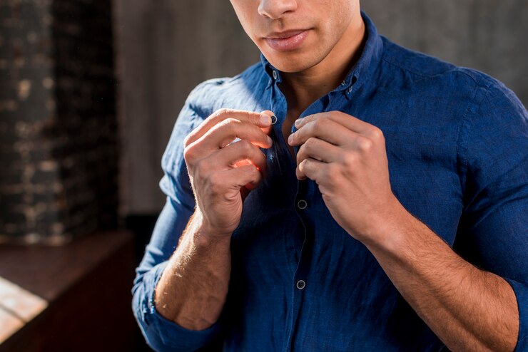 Free Photo close-up of a young man buttons up his blue shirt