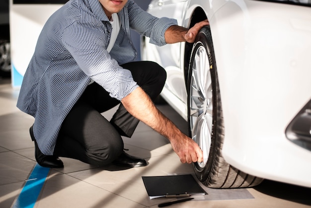 車のタイヤをチェックするクローズアップの若い男