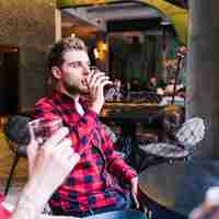 Foto gratuita primo piano di un giovane uomo che beve la birra con il suo amico nel pub