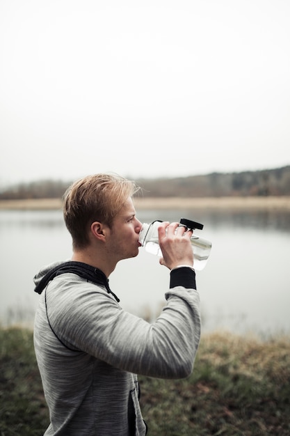 Foto gratuita primo piano di acqua potabile del giovane dalla bottiglia