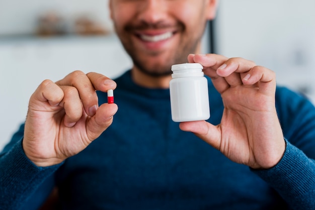 Close-up young man holding pill and pill recipient