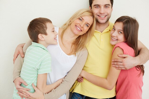 Close-up of young man hugging his wife and children