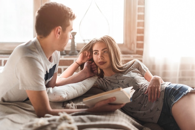 Free photo close-up of a young man loving her girlfriend holding book in his hand