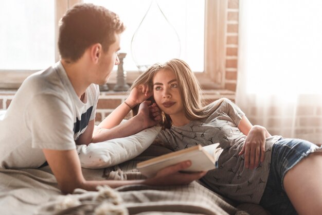 Close-up of a young man loving her girlfriend holding book in his hand