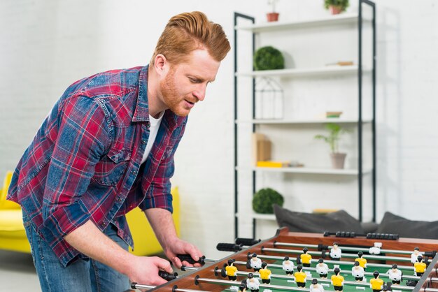 Close-up of young man playing the football table soccer game at home