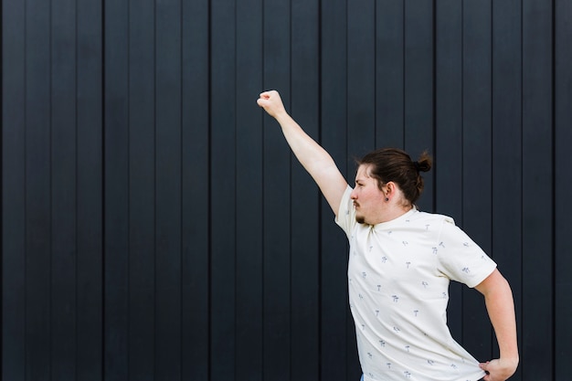 Free photo close-up of a young man raising his arms against black wall