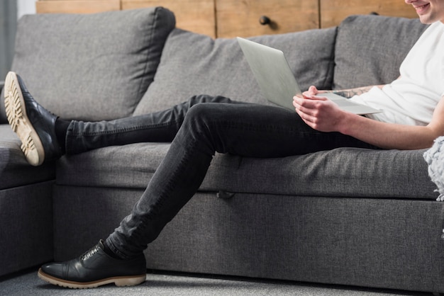 Free photo close-up of a young man sitting on sofa looking at laptop