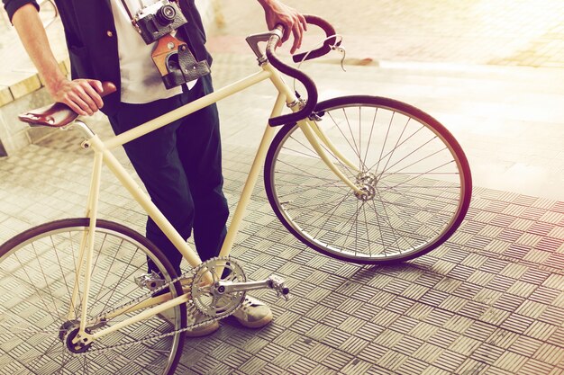 Крупным планом молодой человек с классическим велосипедом и камерой