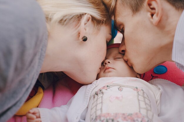 Close-up of young parents kissing their daughter