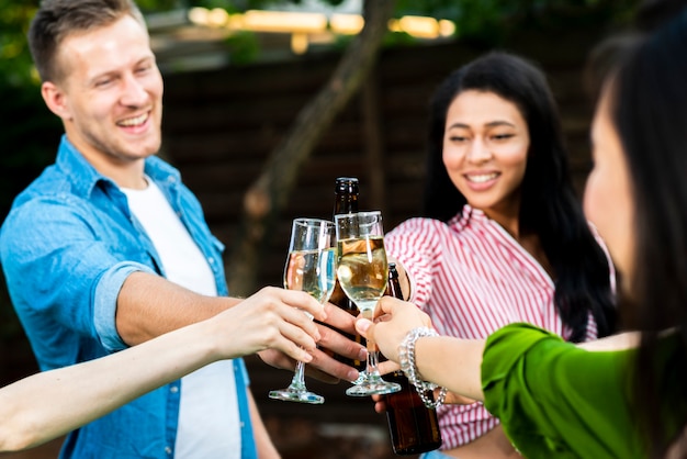 Close-up young people toasting drinks together