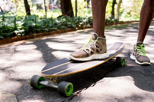 公園でスニーカーで若いスケートボーダーの足をクローズアップ