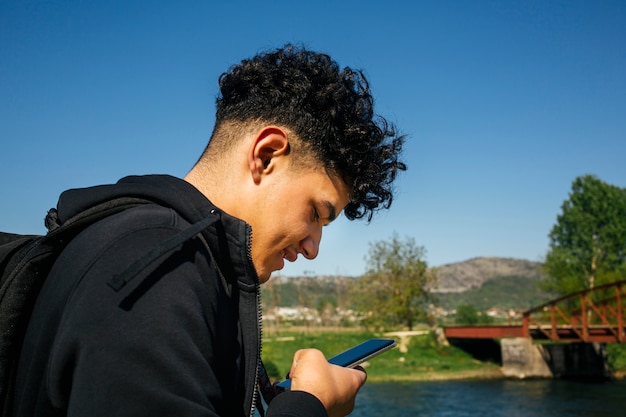 Close-up of young smiling man using smartphone