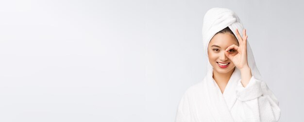 Close up of young smiling woman with finger ok gesture on eyes isolated on white background