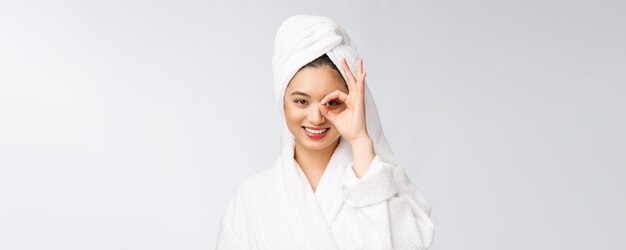 Close up of young smiling woman with finger ok gesture on eyes isolated on white background