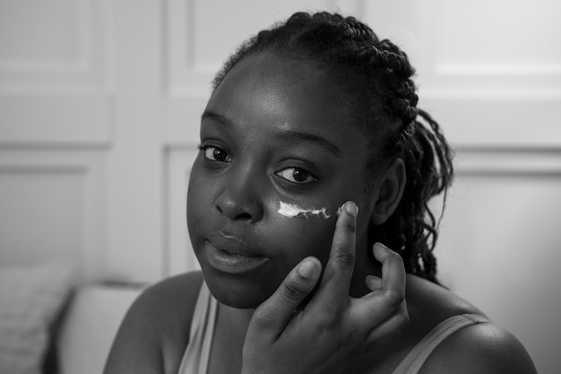 Close up young woman applying face cream