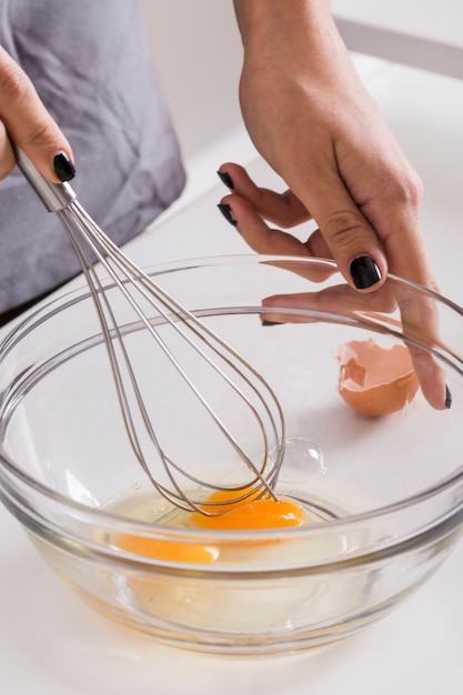 Close-up of a young woman beating the eggs with whisk