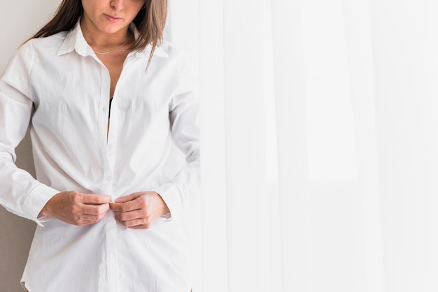 Free photo close-up of young woman buttoning the white shirt