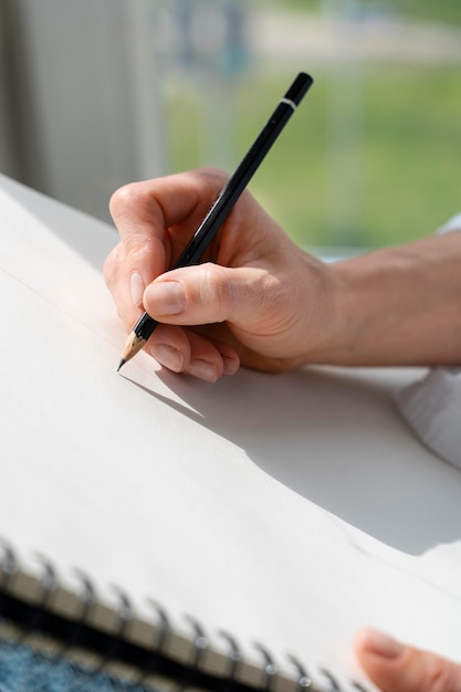 Free photo close-up of a young woman drawing at home near the window