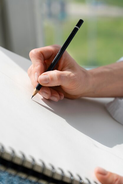 Close-up of a young woman drawing at home near the window