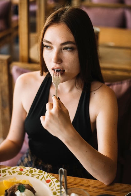 Free photo close-up of young woman eating dessert with fork
