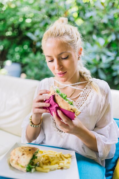 Close-up of young woman eating sandwiches