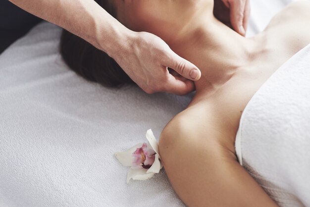 Крупным планом молодая женщина получает массаж в салоне красоты. Процедуры для кожи и тела.