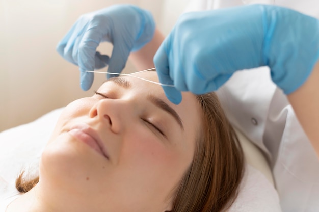 Close-up of young woman getting an eyebrow treatment