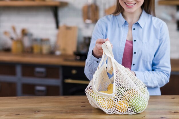 Close-up young woman holding bag with fresh fruits