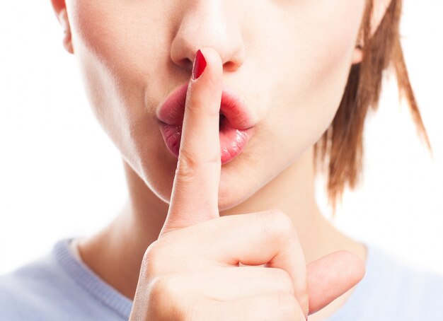 Close-up of young woman holding finger on lips