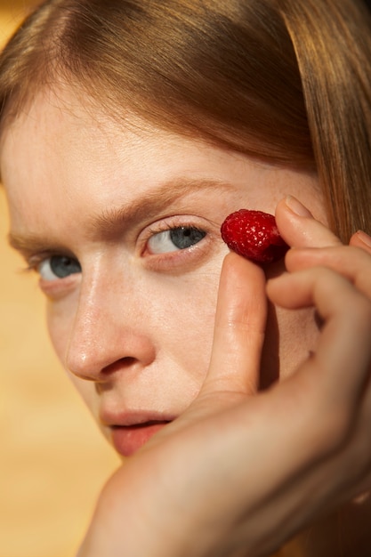 Free photo close up young woman holding fresh raspberry