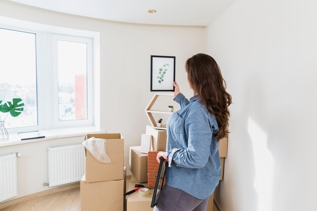 Close-up of a young woman holding leaves picture frame in her new home