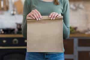 Free photo close-up young woman holding paper bag