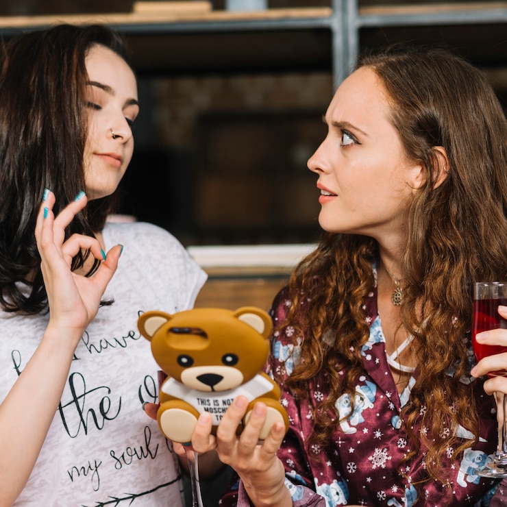 Free Photo close-up of a young woman looking at her friend showing ok sign